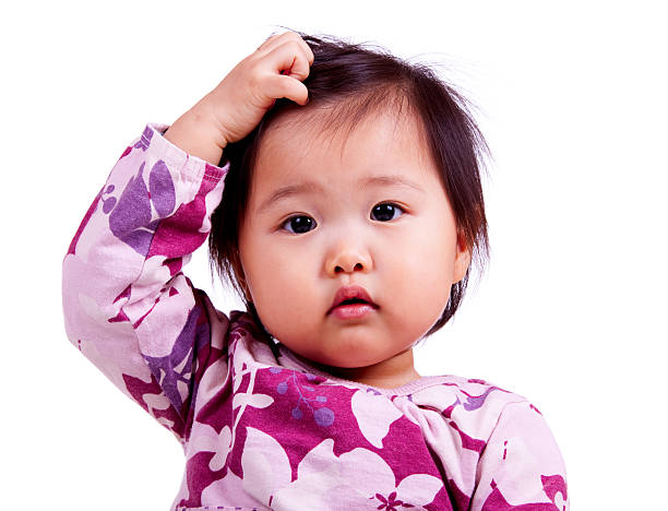 Cute Asian baby, scratching her head and looking confused, isolated on white.