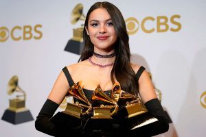 Olivia Rodrigo, at the 64th annual Grammy awards, holds up the three trophies that she won for Best New Artist, Best Pop Solo Performance, and Best Pop Vocal Album.