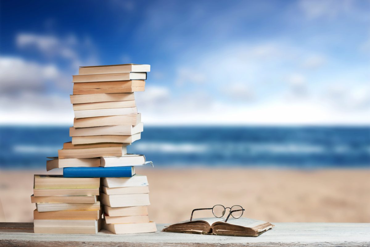 Stack of Travel Guides before a Beach